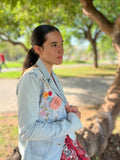 Chaqueta Bruma en denim claro, con flores bordadas sobre tul, tachuelas y encaje antiguo cosido a mano en la espalda.