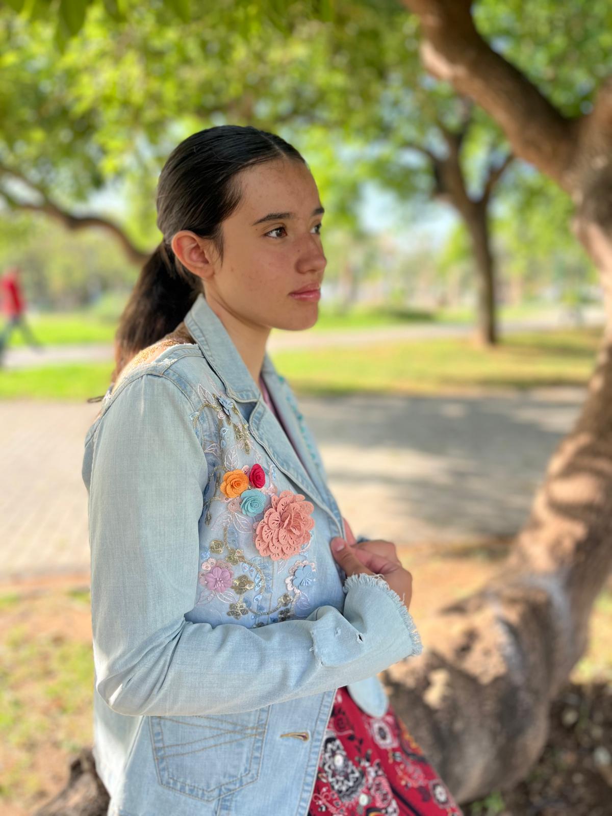 Chaqueta Bruma en denim claro, con flores bordadas sobre tul, tachuelas y encaje antiguo cosido a mano en la espalda.